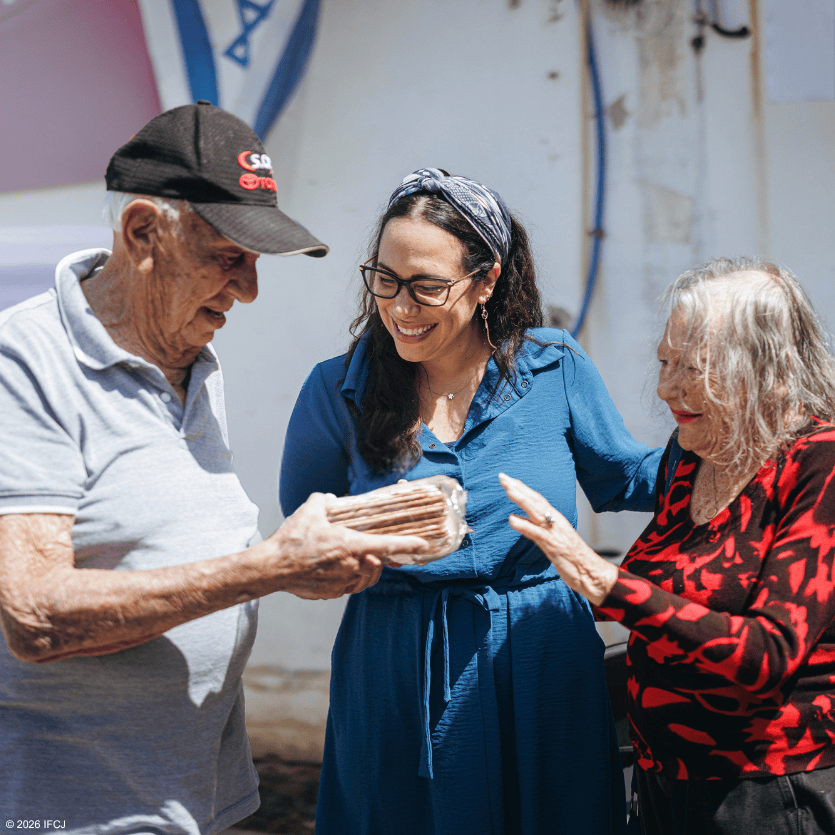 Three people sharing a joyful moment, with an elderly man receiving a gift from a woman, symbolizing compassion and kindness.