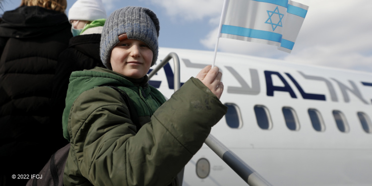 Young boy waving an Israeli flag right before he's about to board a plane.