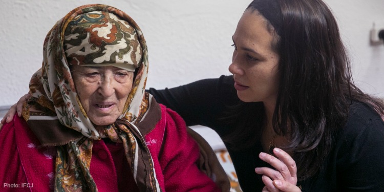 Yael Eckstein holding the hand of an elderly Jewish woman.