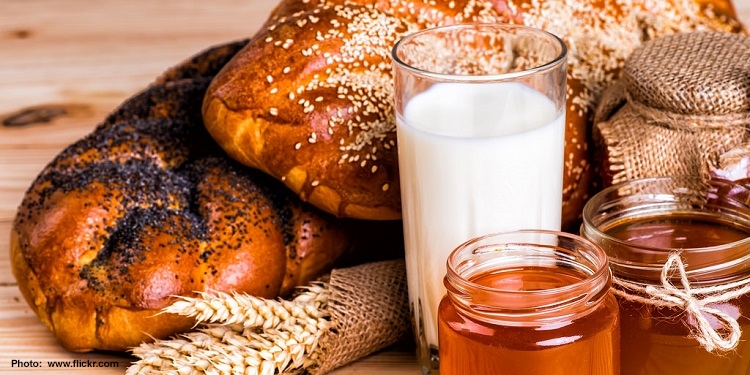 Bread, milk, honey, and wheat laid out on a table.