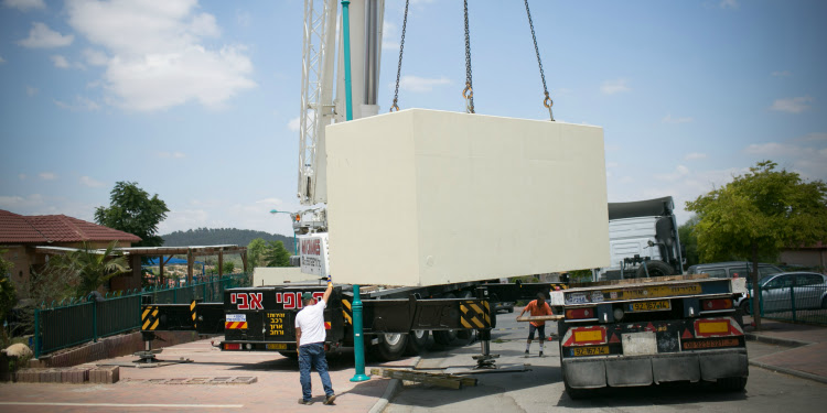 Cranes moving a mobile bomb shelter.