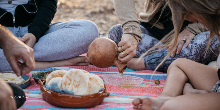 People gathered around pita bread and olive oil