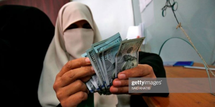 Person holding up one-hundred-dollar bills to the camera as they flip through them.