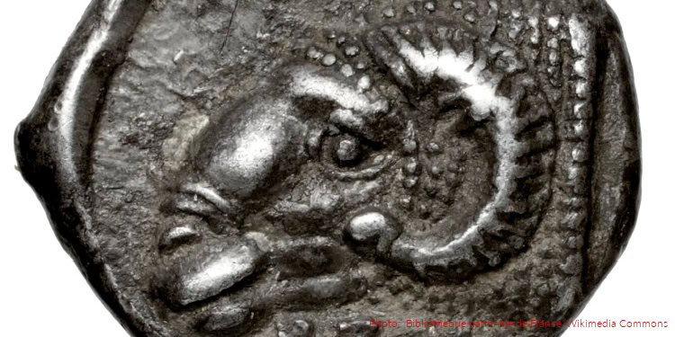 Close-up of an ancient coin featuring a detailed animal head, possibly a ram or goat, with intricate engravings and signs of age, reflecting trade and history in ancient Israel.
