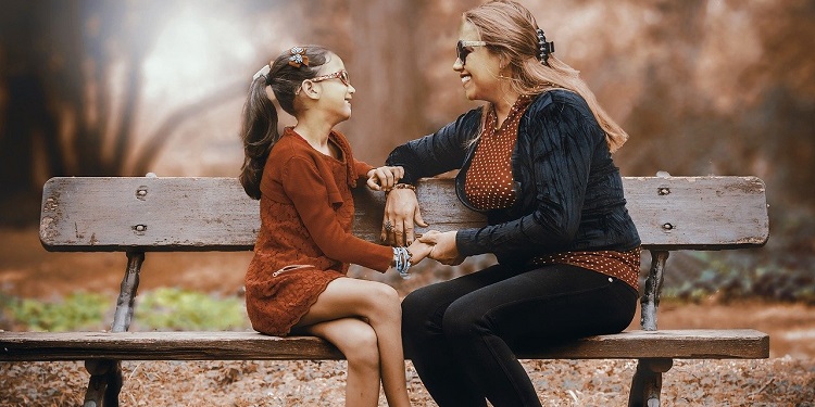 A mother and daughter smiling while sitting on a bench