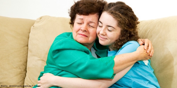 Girl hugging and blessing elderly woman