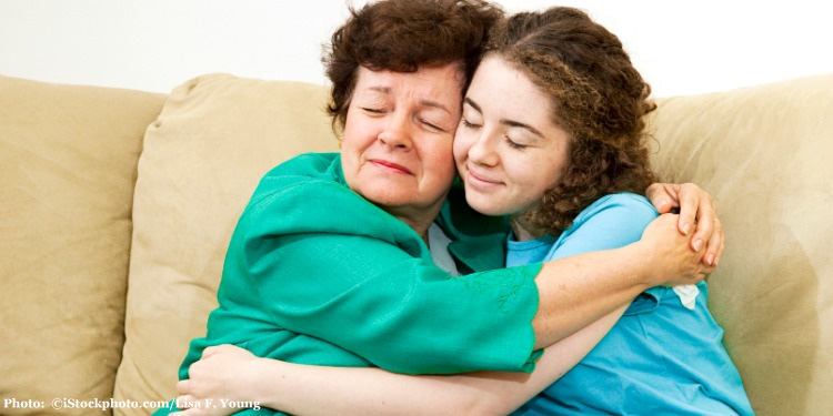 Mother and teenage daughter giving each other a big hug.