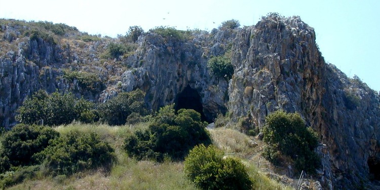 Mount Carmel, with an opening to a cave with green shrubbery and trees around it.
