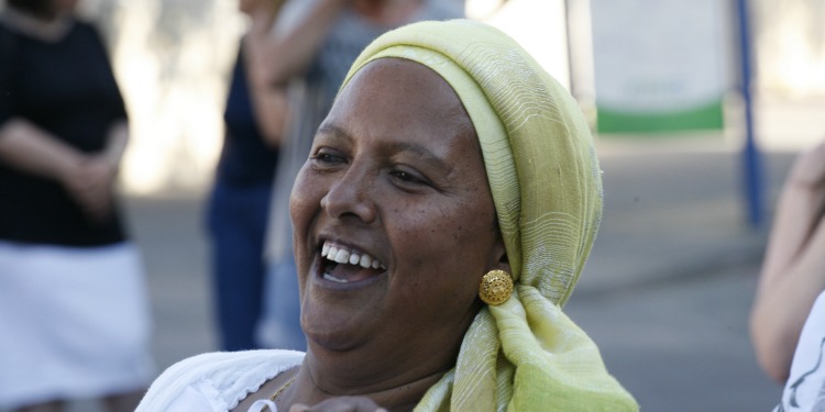 Woman in a green headscarf smiling and laughing.