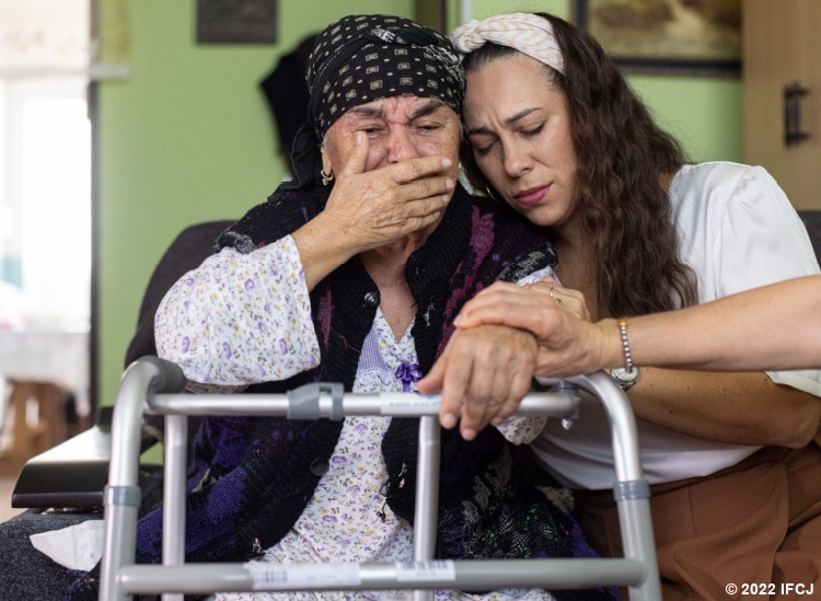 Yael Eckstein embracing elderly woman as she cries.