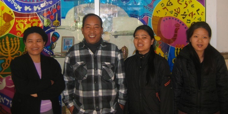 A family of four in front of a Hannukah poster.