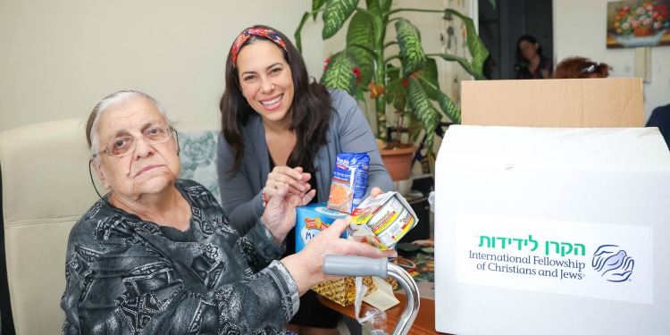 Elderly Jewish woman sitting with Yael Eckstein while going through an IFCJ food box.