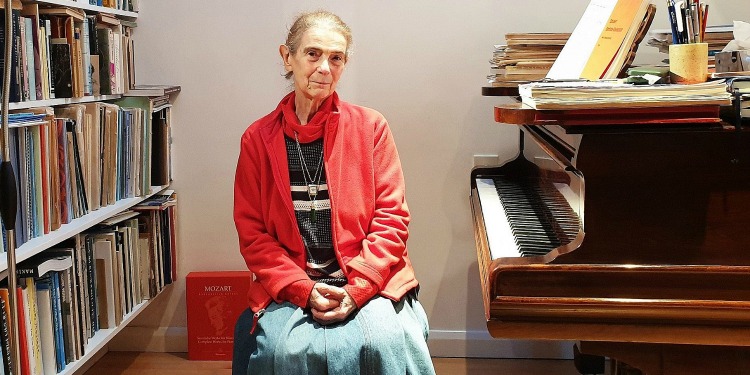 Elderly women sitting next to a piano.