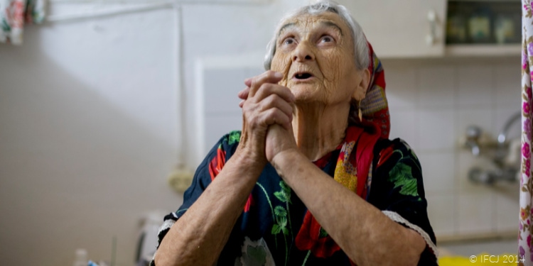 Elderly woman clasping hands and looking up