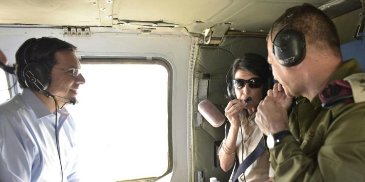 Nikki Haley in a helicopter tour over Israel with a soldier and a man in a blue button down.