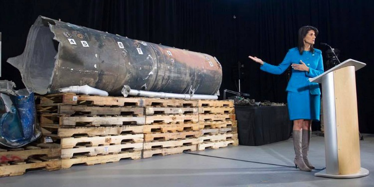 Nikki Haley speaking at a podium with a rocket behind her.