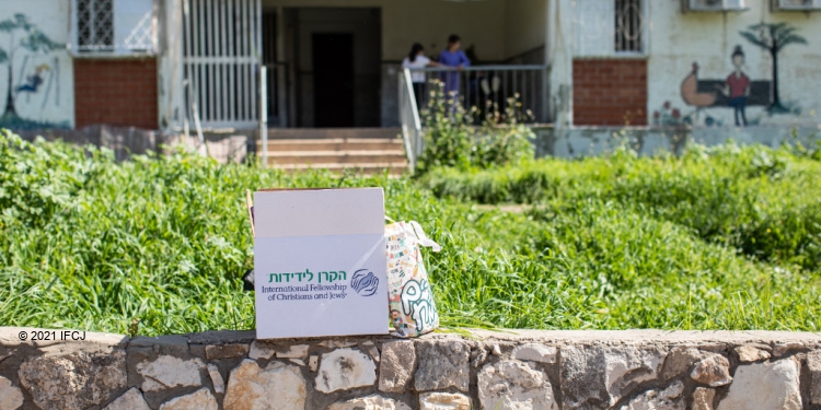 An IFCJ branded food box sitting on a ledge outside of an apartment building.