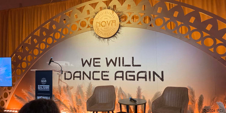 IFCJ Staff Visit to The Nova Exhibition - Chicago, IL - November 17, 2025 stage with white chairs - backdrop that reads We Will Dance Again -