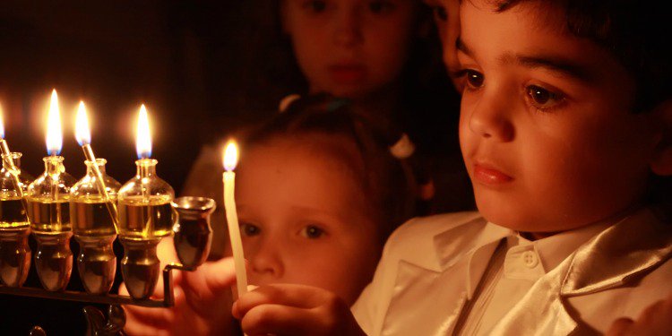 Small child lighting candles during Hanukkah.