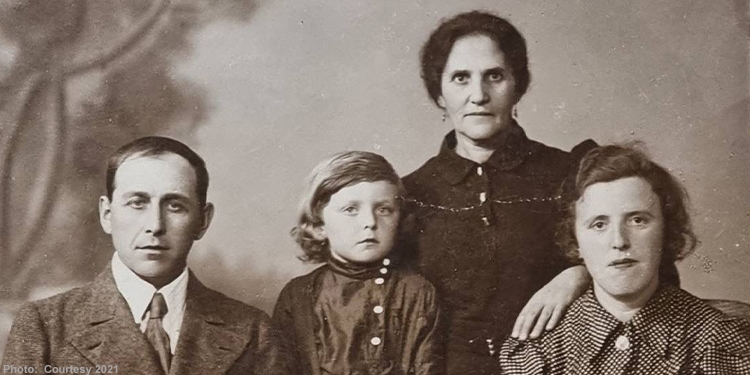Brown and white image of a family of four looking directly into the camera.