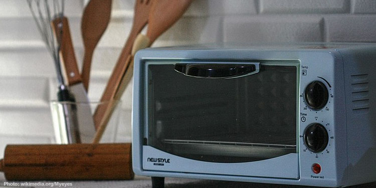 Microwave oven with wooden spoons in the background
