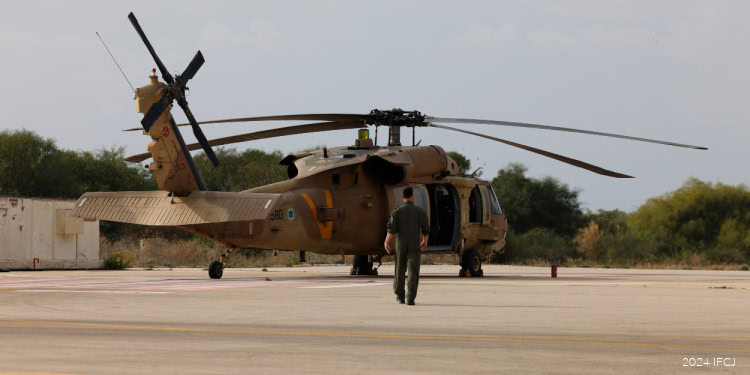 Clay Travis Tour of Israel - Palmachim IAF Base - December 12, 2024 pilot in jumpsuit seen from behind walking toward tan helicopter