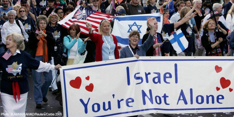 Women walking in a parade with a banner that reads Israel You're Not Alone.