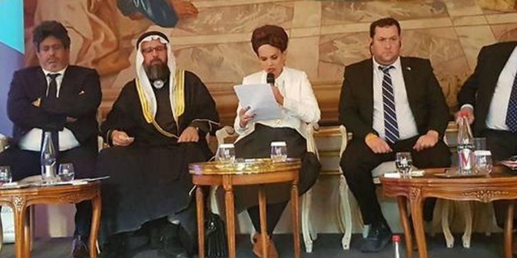 Five people sitting at small tables with drinks in front of them.