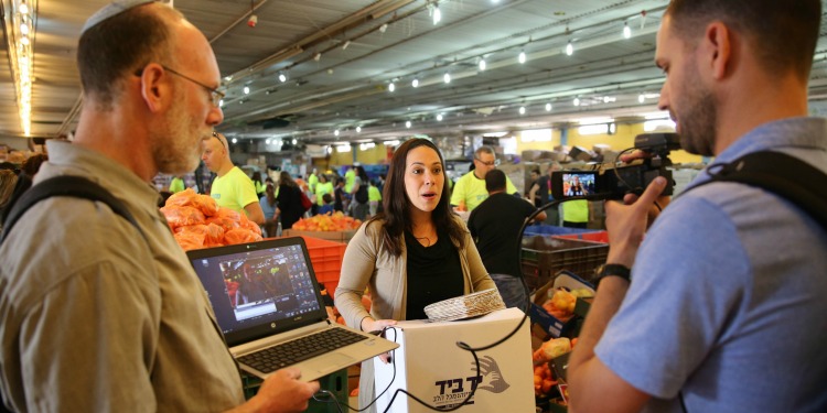 Yael Eckstein holding a food box as a camera man is recording her.