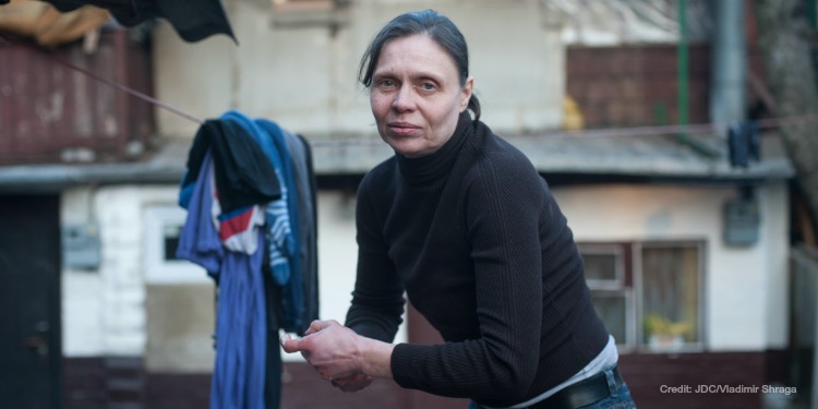 Middle aged woman hanging clothes on a line outside.