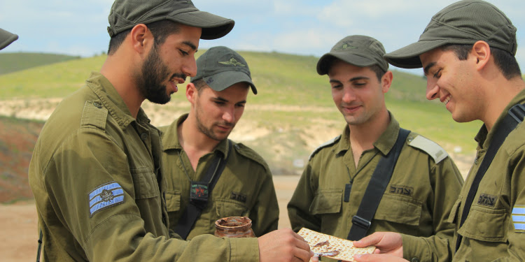 Four IDF soldiers looking over a piece of paper together.
