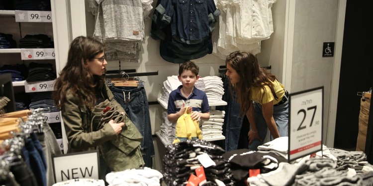 A young child shopping for clothes, which was provided by IFCJ donors.