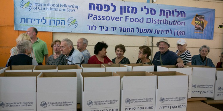 Line of elderly people next to IFCJ branded boxes.