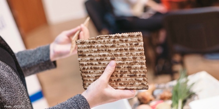 Hands holding broken Matzah.