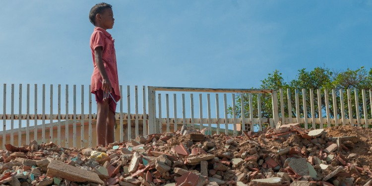 Young child in red clothing standing on top a pile of bricks.