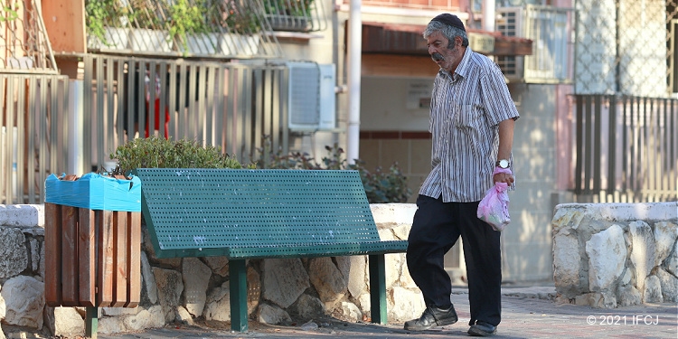 Poor elderly man walking down street by himself in Israel,