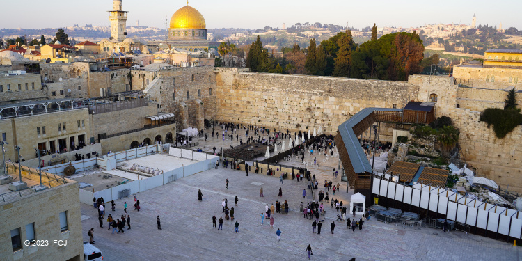 Aerial view of a large crowd of people walking towards the Western Wall to pray.