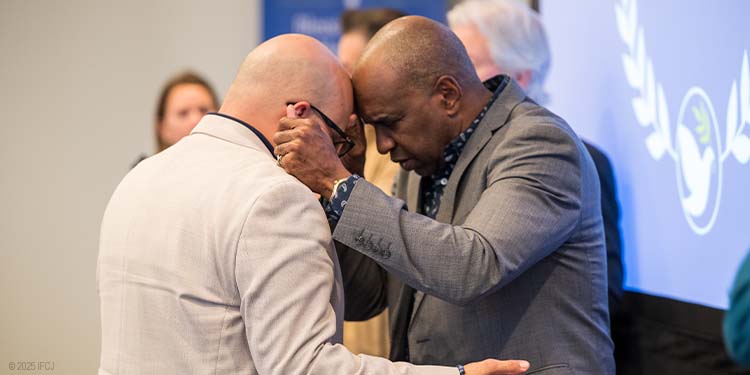 Pastor Roger Cheeks praying with an IFCJ staff member