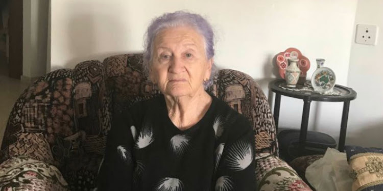 Elderly Jewish woman sitting in a chair looking into the camera.