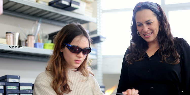 A girl in glasses next to Yael Eckstein who is smiling while looking down.