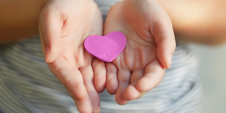 Hands cupped together holding a felt shaped heart.