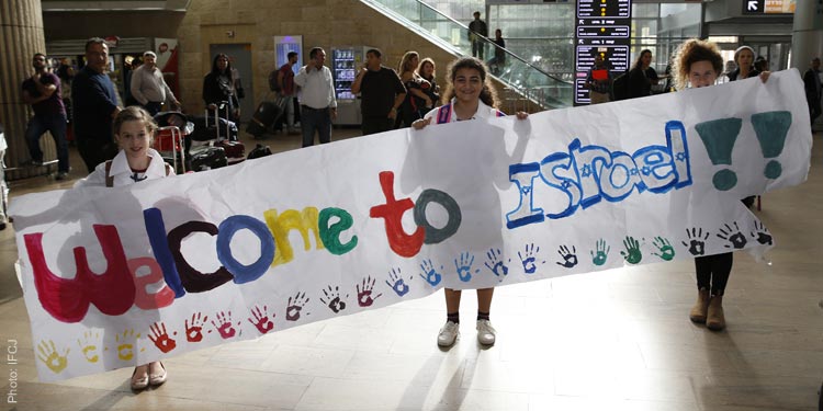 Three young girls holding a Welcome to Israel banner.