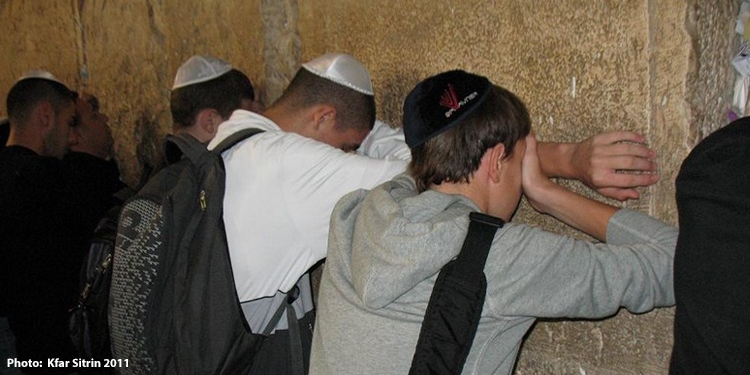 Jewish men covering their eyes in prayer at the Western Wall.