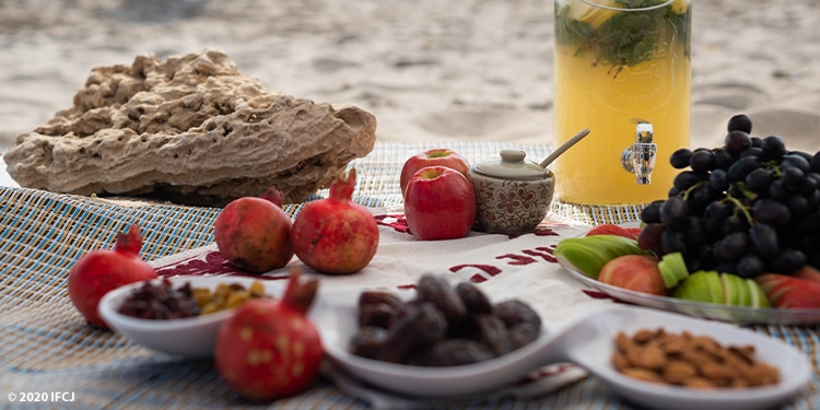 Rosh Hashanah meal spread out on a blanket with pomegranates and honey.