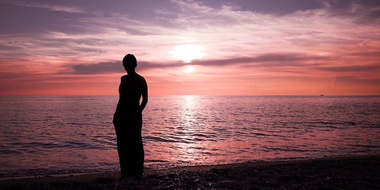 Silhouette of a person against a red and purple sunset.