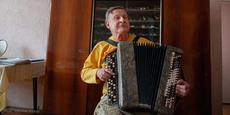 elderly man playing accordion, yellow shirt