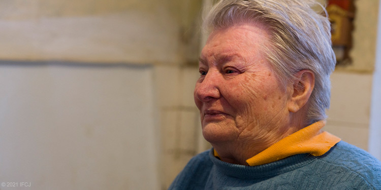 elderly woman wearing multiple layers of clothes, blue sweatshirt, yellow shirt