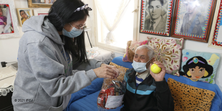 An IFCJ staff member with an elderly Jewish man during Purim.