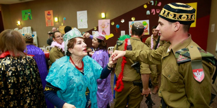 A woman and a young soldier dancing together at a Purim party.