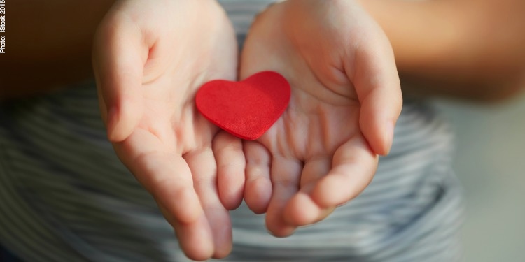 Cut out red heart in the middle of two hands cupped together.